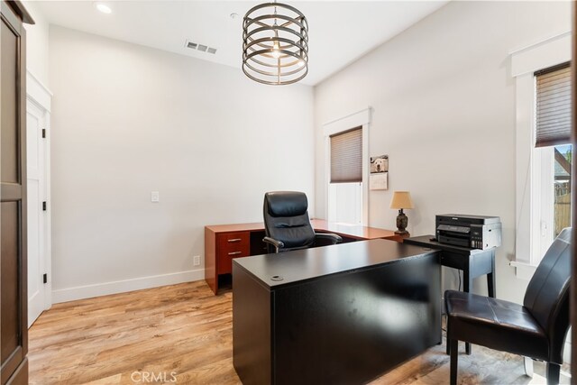 office space with light hardwood / wood-style flooring and a chandelier