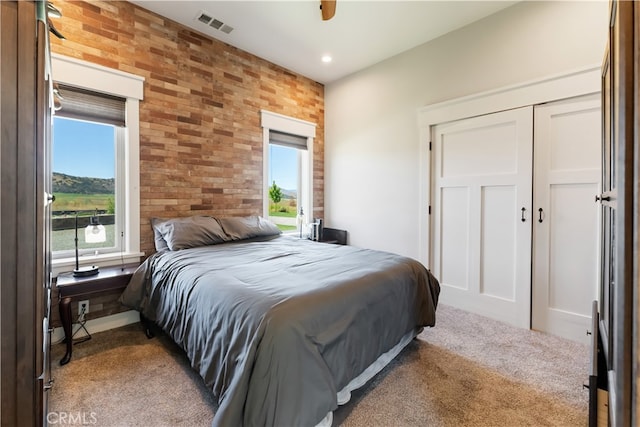 bedroom featuring a closet, ceiling fan, brick wall, and carpet flooring