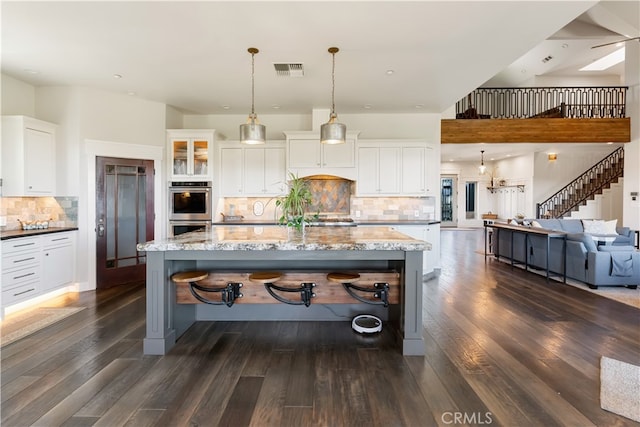 kitchen with white cabinets, tasteful backsplash, decorative light fixtures, and dark wood-type flooring