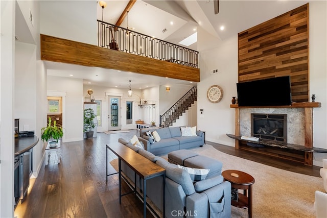 living room featuring dark wood-type flooring, beam ceiling, high vaulted ceiling, and a premium fireplace