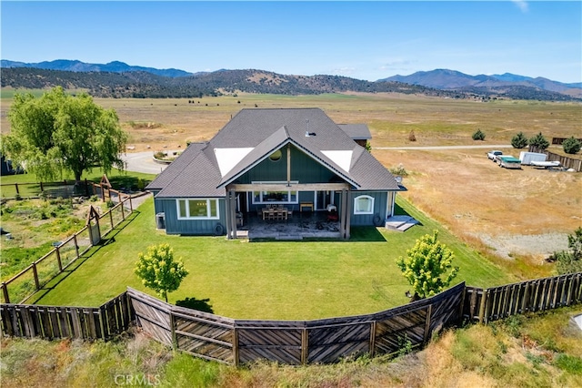 rear view of property featuring a yard, a mountain view, a rural view, and a patio