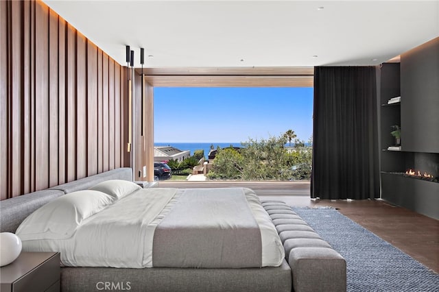 bedroom featuring dark hardwood / wood-style floors and a water view