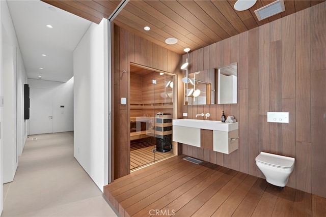 bathroom featuring walk in shower, wood walls, vanity, and toilet