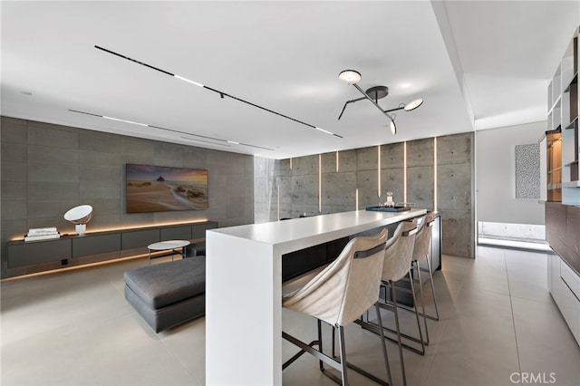 kitchen featuring a kitchen breakfast bar, tile walls, white cabinetry, and a kitchen island