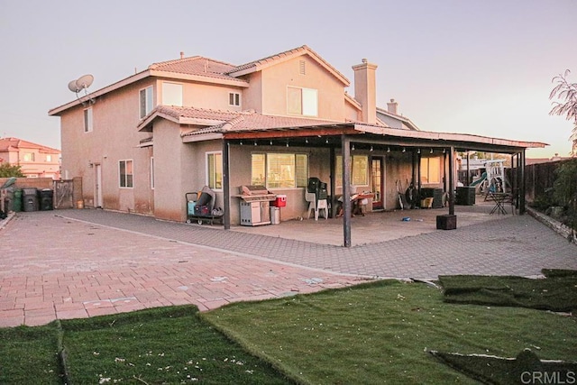 back house at dusk with a patio area