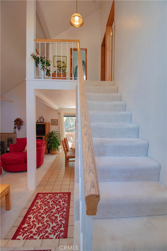 stairway with tile patterned flooring and high vaulted ceiling