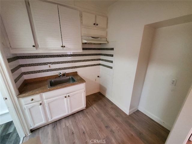 kitchen featuring light hardwood / wood-style floors, white cabinets, sink, and backsplash