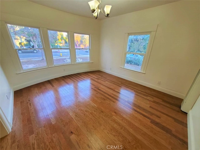 empty room featuring a notable chandelier and hardwood / wood-style floors