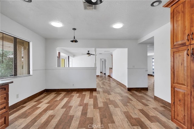 spare room with light wood-type flooring, a textured ceiling, and ceiling fan