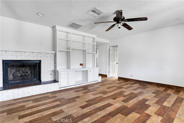 unfurnished living room with ceiling fan, a textured ceiling, a fireplace, and dark hardwood / wood-style flooring