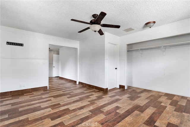 unfurnished bedroom with a textured ceiling, ceiling fan, dark wood-type flooring, and a closet