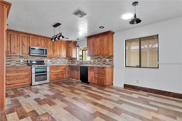 kitchen with hanging light fixtures, light hardwood / wood-style floors, decorative backsplash, stainless steel appliances, and a textured ceiling