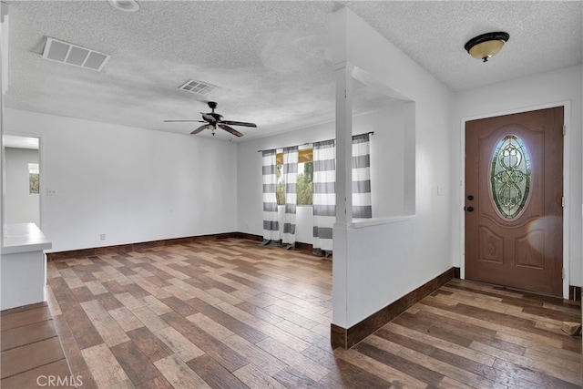 entryway with a textured ceiling, a healthy amount of sunlight, ceiling fan, and dark wood-type flooring