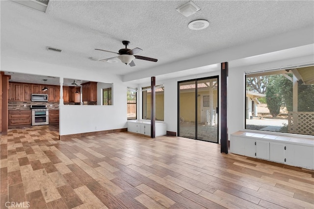 unfurnished living room featuring a textured ceiling, ceiling fan, and light hardwood / wood-style flooring