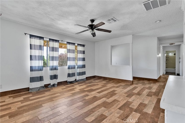 empty room featuring ceiling fan, a textured ceiling, and wood-type flooring