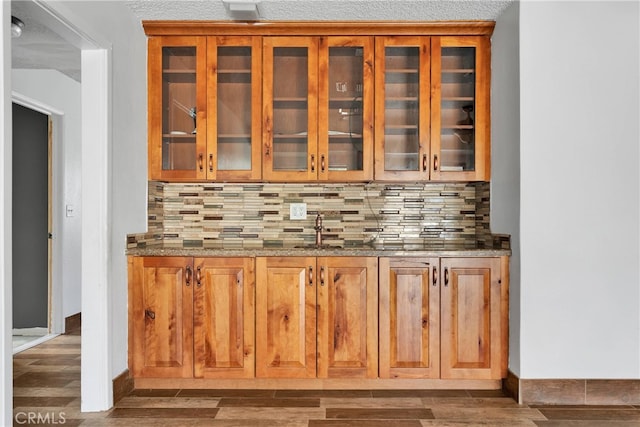 bar with a textured ceiling, stone countertops, dark wood-type flooring, and tasteful backsplash