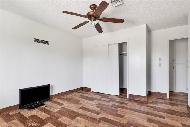 unfurnished bedroom with ceiling fan, a textured ceiling, and dark wood-type flooring