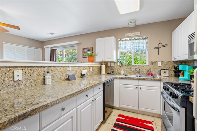 kitchen with white cabinetry, stainless steel gas range oven, light tile patterned floors, backsplash, and sink