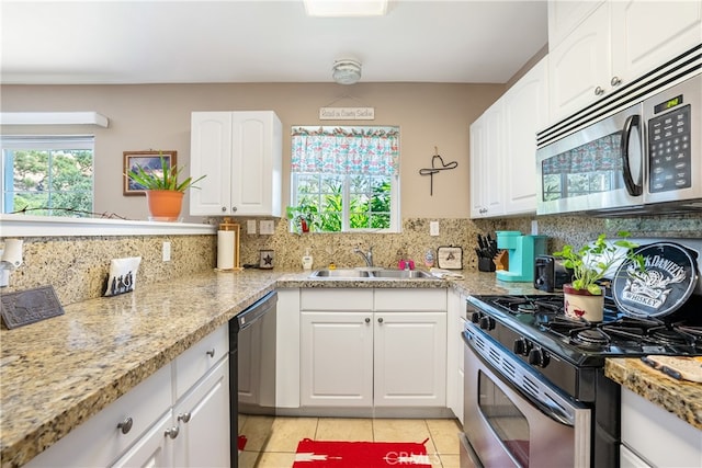 kitchen featuring white cabinetry, light tile patterned floors, appliances with stainless steel finishes, decorative backsplash, and sink