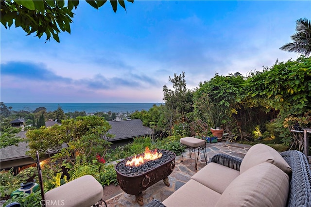 patio terrace at dusk featuring a water view and an outdoor fire pit