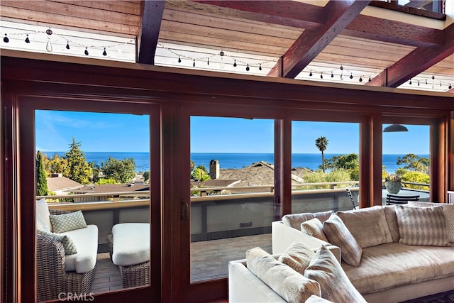 living room with a water view, beamed ceiling, and rail lighting