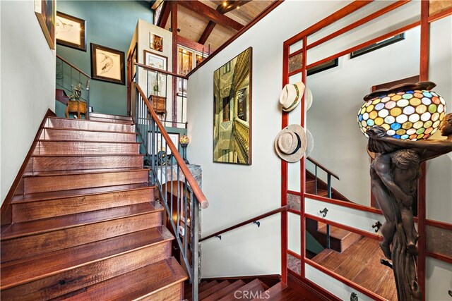 stairway with wooden ceiling, wood-type flooring, and beam ceiling