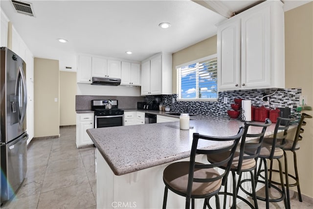 kitchen featuring a breakfast bar, appliances with stainless steel finishes, white cabinetry, and extractor fan