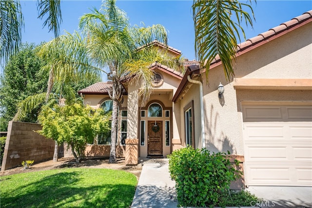 view of exterior entry featuring a lawn and a garage