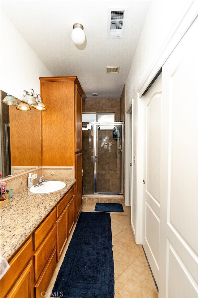 bathroom featuring tile patterned flooring, a textured ceiling, vanity, and an enclosed shower