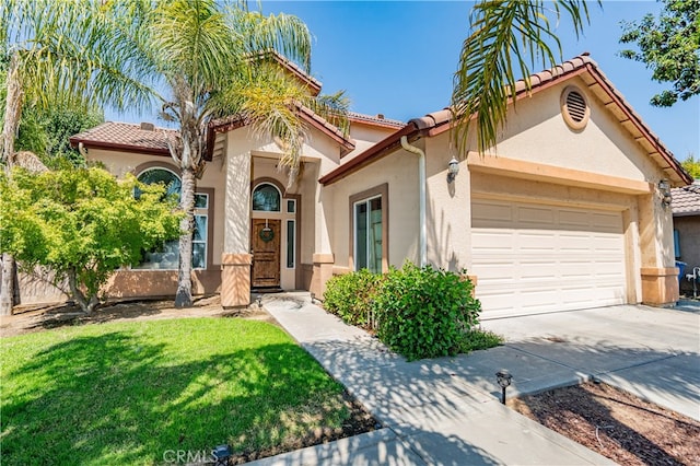 mediterranean / spanish-style house featuring a garage and a front lawn