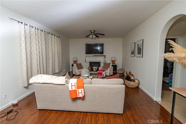 living room featuring ceiling fan and dark wood-type flooring