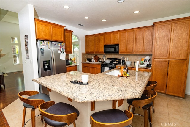 kitchen featuring a breakfast bar area, a center island, and black appliances