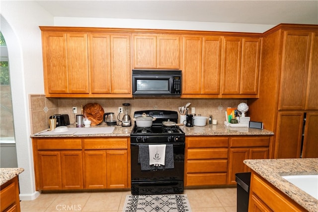 kitchen with decorative backsplash, light tile patterned floors, and black appliances