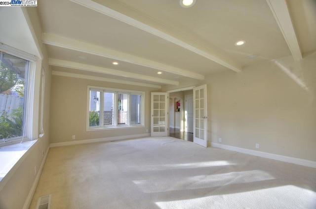 empty room with beam ceiling, french doors, and light colored carpet