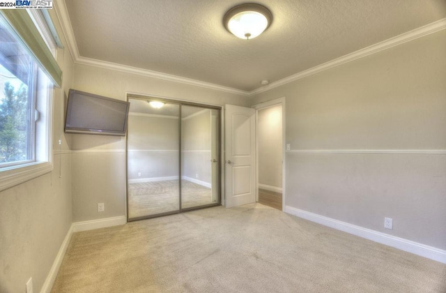 unfurnished bedroom featuring multiple windows, light colored carpet, a closet, and ornamental molding