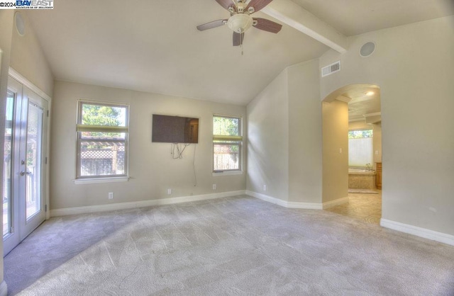 carpeted spare room featuring vaulted ceiling with beams, a healthy amount of sunlight, ceiling fan, and french doors