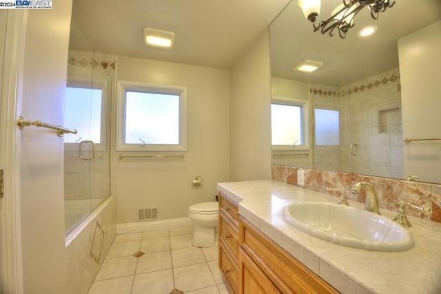 bathroom with tile patterned flooring, vanity, a chandelier, and plenty of natural light