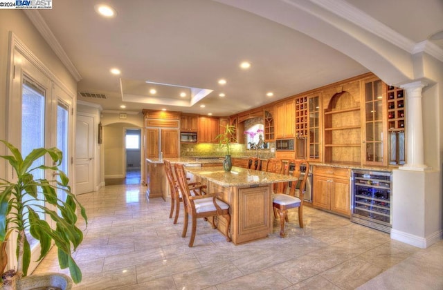 dining space featuring bar, ornamental molding, wine cooler, and ornate columns