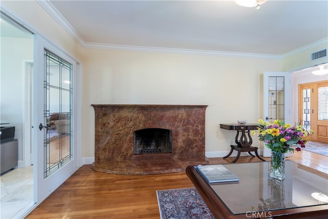 living room with a premium fireplace, wood-type flooring, and ornamental molding