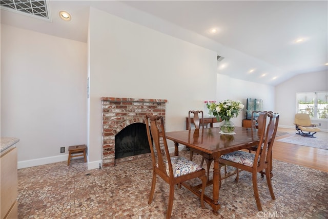 dining room with lofted ceiling and a brick fireplace