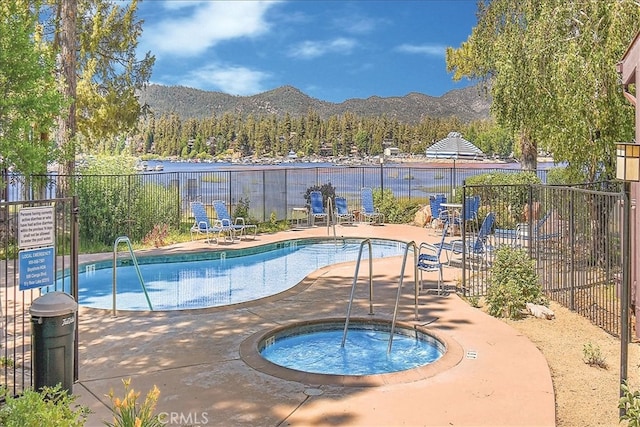 view of swimming pool with a mountain view, a community hot tub, and a patio