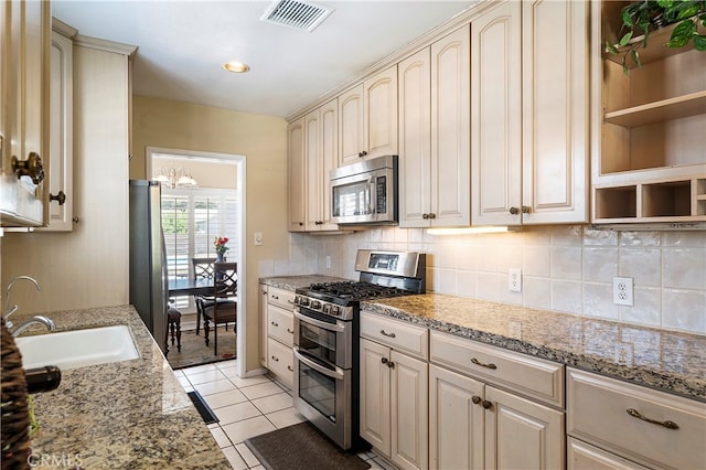 kitchen featuring light stone counters, appliances with stainless steel finishes, light tile patterned floors, and cream cabinets