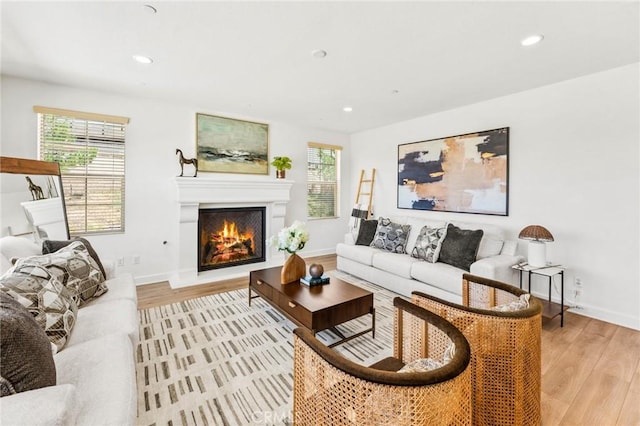 living room with a lit fireplace, light wood finished floors, and recessed lighting