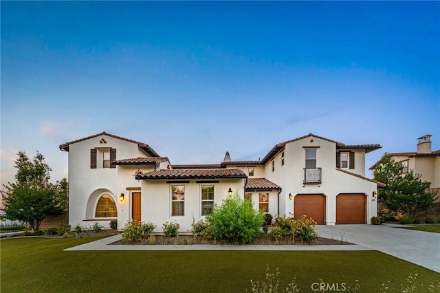 mediterranean / spanish-style house with a garage, concrete driveway, a front yard, a tile roof, and stucco siding