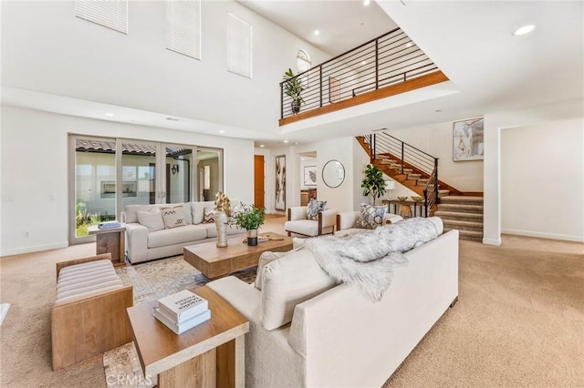 living room with light carpet, stairs, a towering ceiling, and baseboards