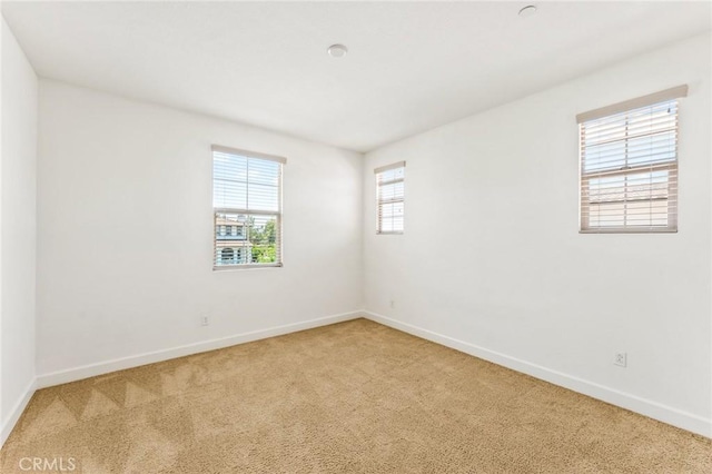 unfurnished room with baseboards and light carpet