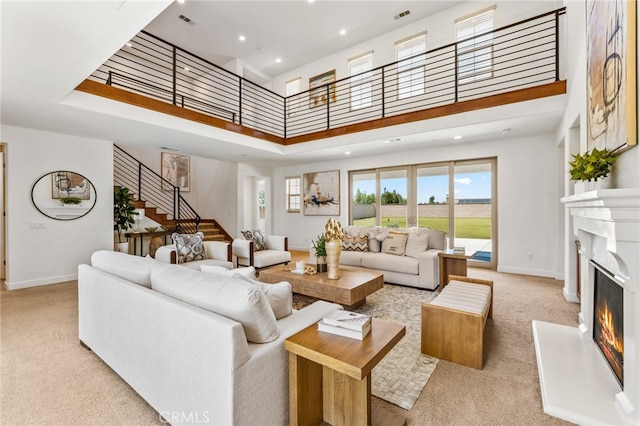 carpeted living room with a fireplace and a towering ceiling