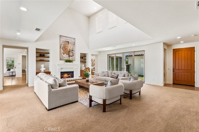 living room with built in shelves, light carpet, and a high ceiling