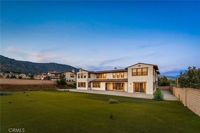 rear view of property with a patio area, a mountain view, and a yard