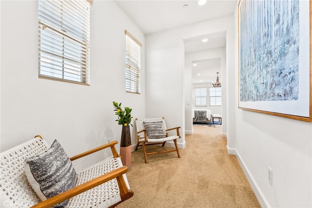 living area with light colored carpet and a notable chandelier